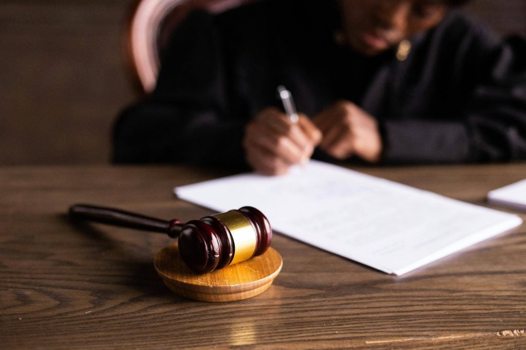 Photo d'un juge qui signe une feuille et de son marteau
